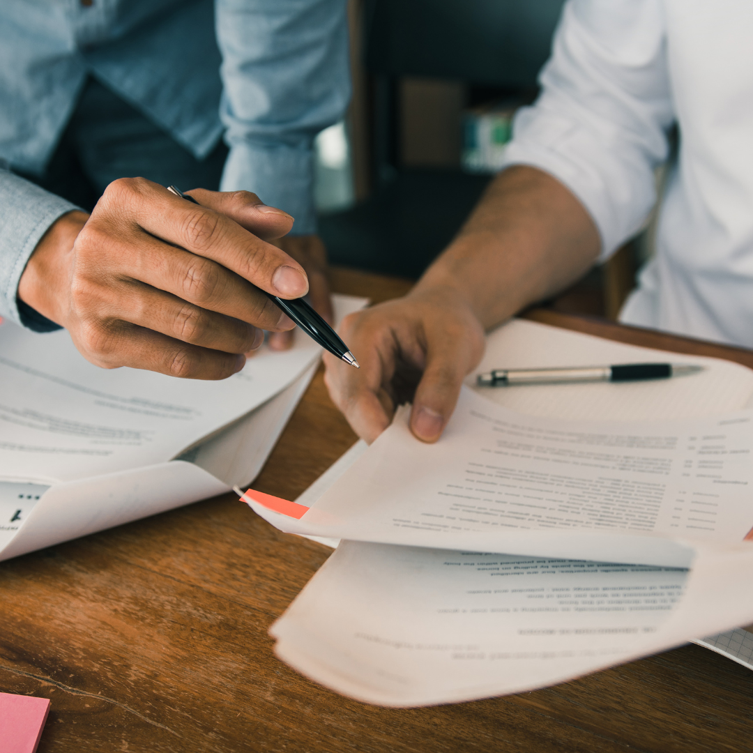 Two people reading a document with a pen