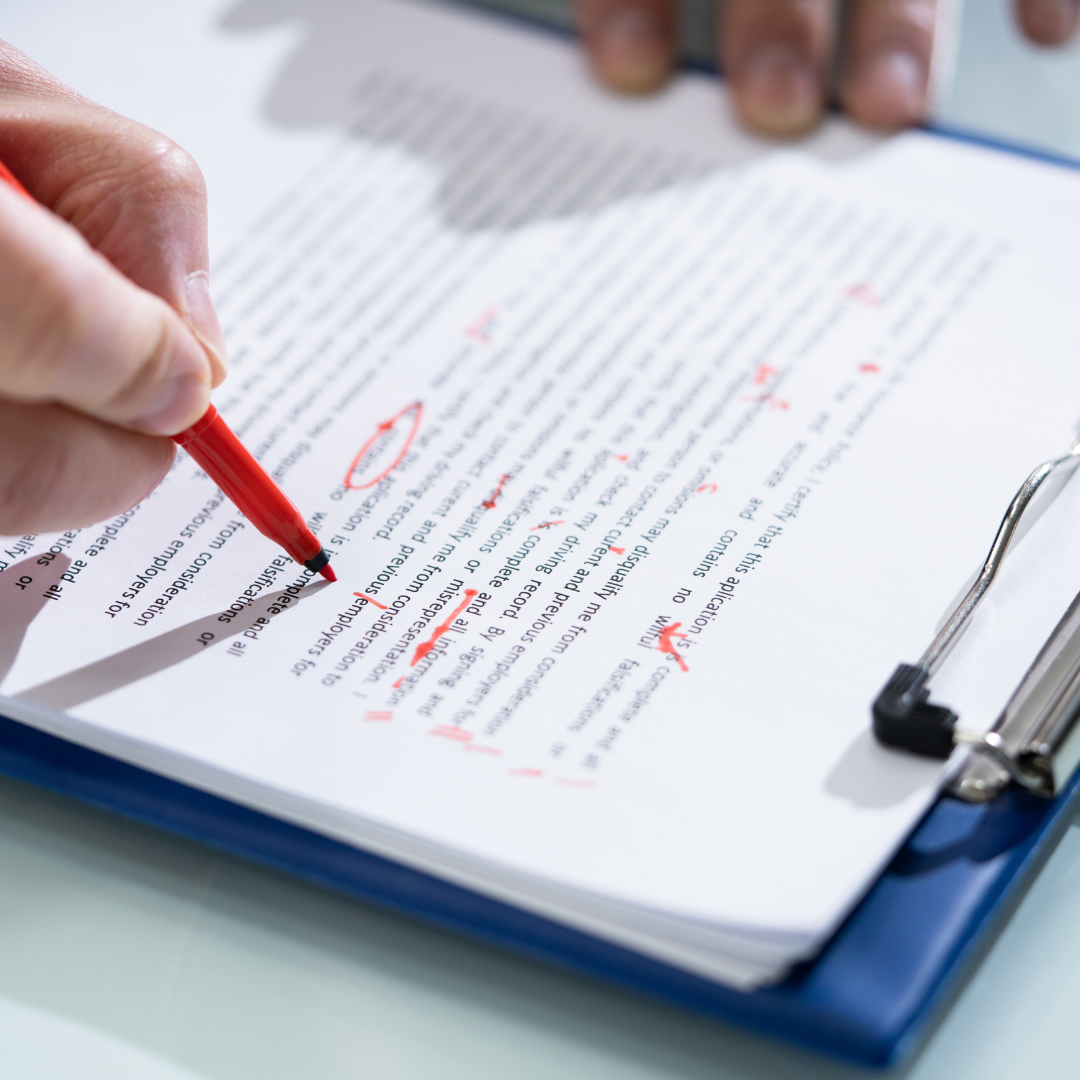 Someone writing in red pen on a document