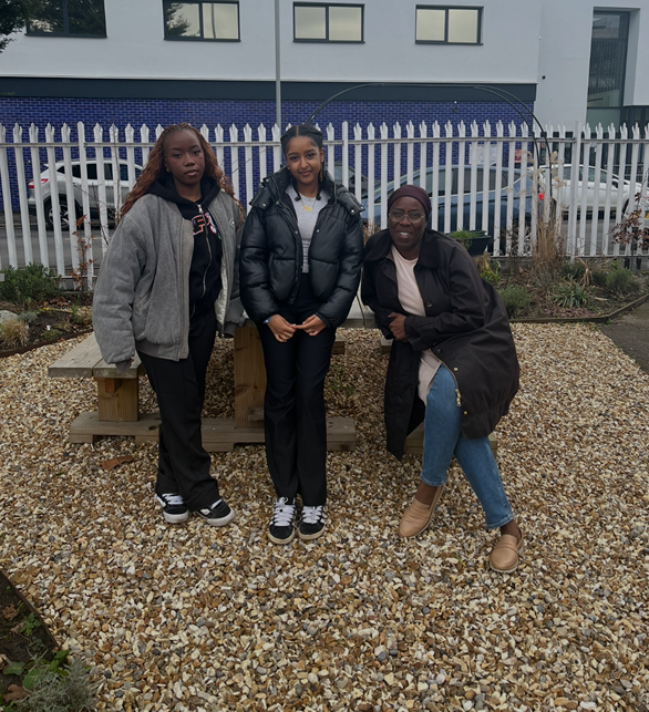Placement students sitting with Michelle in a gravelled area of the Brotherhood Peace Garden